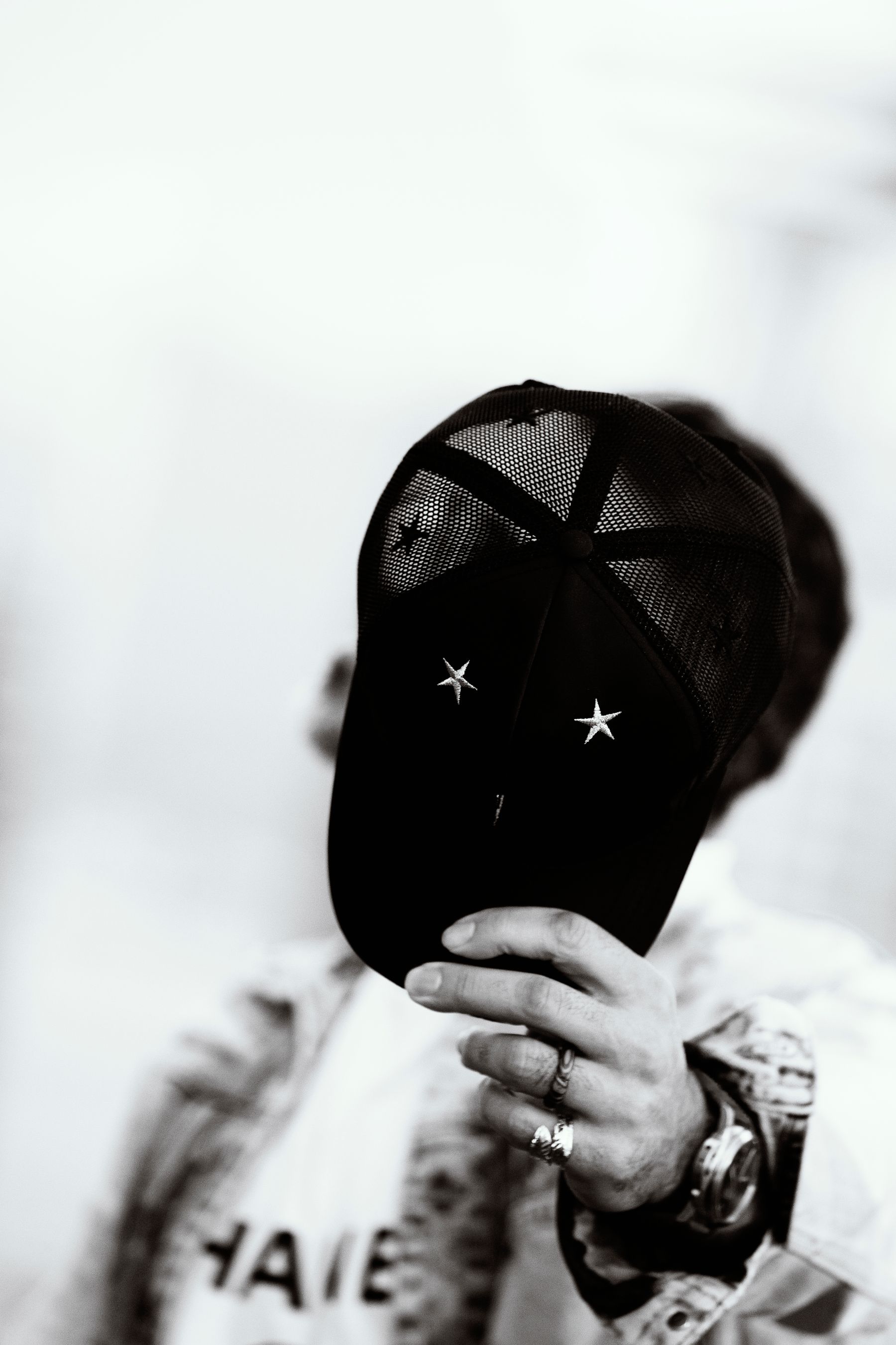 Black-and-white product photograph of a black mesh cap with two embroidered white stars