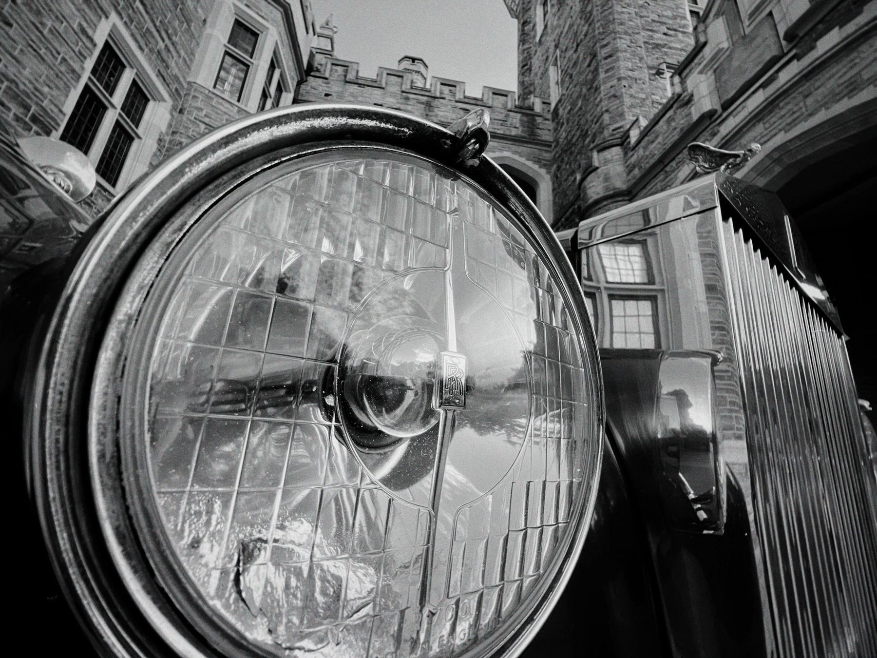 Black-and-white close-up of a classic Rolls-Royce headlight and grille